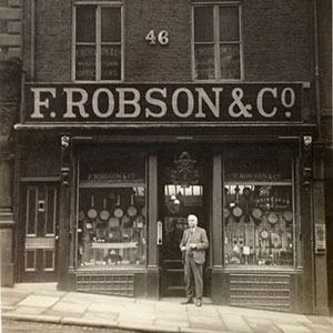 black and white image of a man standing infront of a F.Robson & Co Opticians